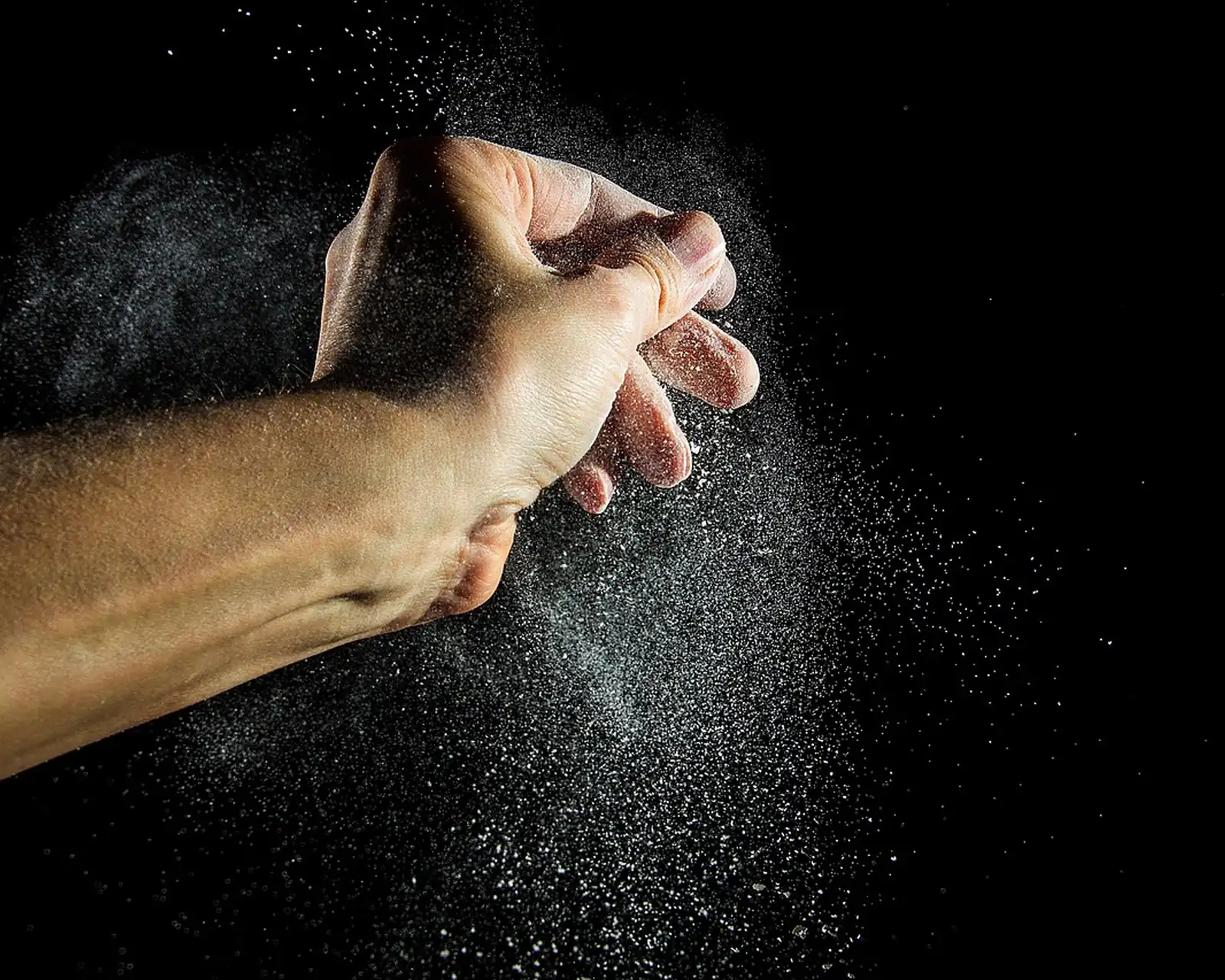 Baker dusting flour in a dark kitchen
